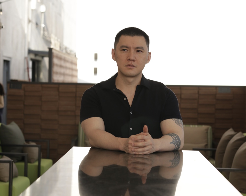 Alan Hsieh seated at a table, hands clasped